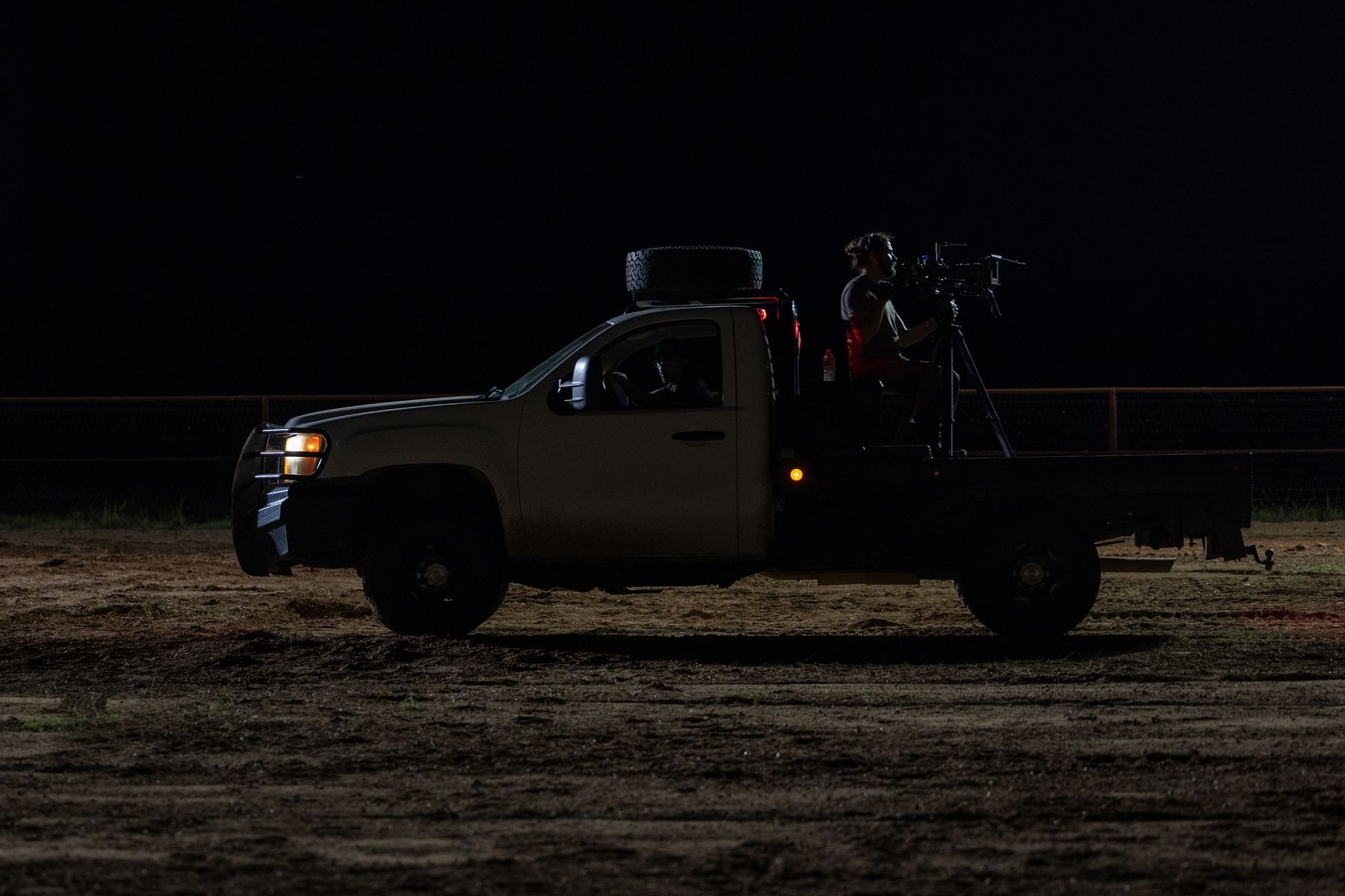 A camera rig mounted on a pickup bed at night in an open field