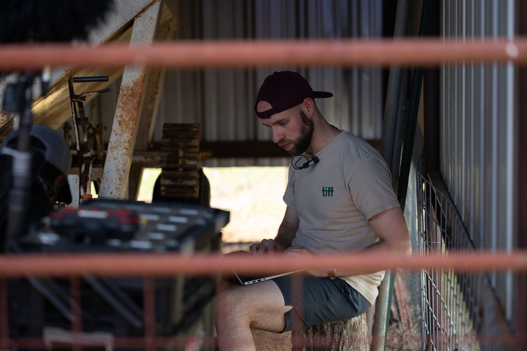 Crew member working at the camera cart behind the rails of a cattle pen
